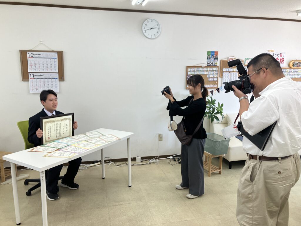 表彰状と10枚の証書を前に取材を受ける大倉和真さん